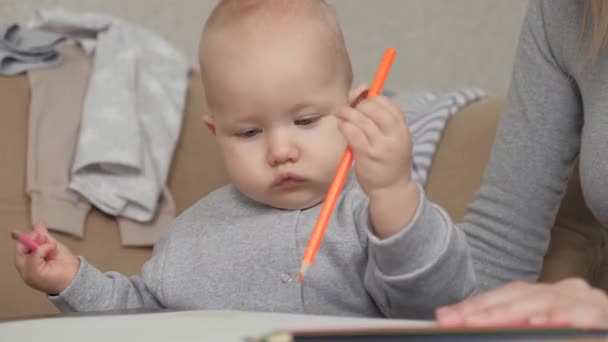 Dzieciaku, syn rysuje kolorowymi ołówkami, chłopiec jest w domu z matką. Córka z entuzjazmem rysuje żółtym ołówkiem na kartce papieru, dziewczynka obok matki. Szczęśliwa rodzina i dziecko — Wideo stockowe