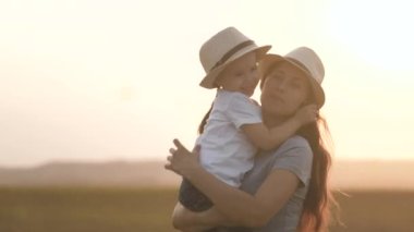Anne ve bebek parkta güneşte sarılıyorlar. Aile ve sağlıklı çocuklar. Mutlu küçük kız parkta annesini, çocuğunu ve annesini seviyor. Aile, anne ve kız dışarıda birlikte oynuyorlar. Bebek annesini seviyor.