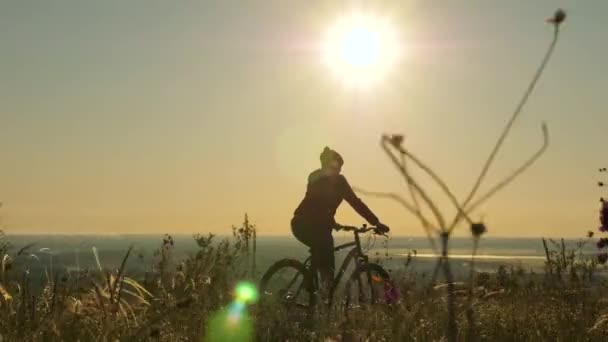 Жінка велосипедиста їде по краю гори, милуючись пейзажем і сходом сонця. Безкоштовний турист катається на велосипеді на природі на сонці. Спортивний спосіб життя. Велосипедні вправи — стокове відео