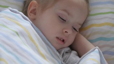 Yatağındaki kreşte uyuyan tatlı bir bebek. Mutlu bebek bebek bebek yatağında uyur ve gülümser. Annem yorgun kızını yatağına yatırdı. Mutlu aile ve çocukluk kavramı. Sağlıklı çocuklar.
