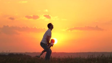 Babam gün batımında mutlu kızını mavi gökyüzüne fırlatıyor. Baba ve sağlıklı çocuk birlikte oynar, güler ve sarılırlar. Kaygısız çocuk gökyüzüne uçuyor. Çocuk ebeveynin kollarında. Babalar izinli. Mutlu aile