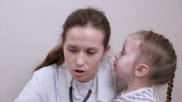 O garoto brinca com o gentil médico infantil e fala com ele. Cuidar de pediatra mulher profissional brincando com criança pequena no escritório. Uma criança pequena é examinada pelo pediatra. Clínicas privadas — Vídeo de Stock