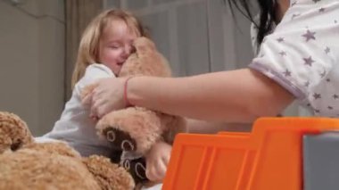 Pijamalı şirin bir bebek evde ebeveynleriyle oynamaktan memnun. Aile kaygısız kızlarıyla oynuyor, mutlu bir çocukluk. Mutlu çocuk gülüyor, anneyle oynuyor, baba evde en sevdiği oyuncaklarla oynuyor.