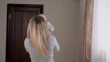 Anne bebekle oynuyor ve onu kollarının arasına alıyor, tatlı bebek evde seviniyor ve gülüyor. Bebek ve anne. Mutlu, genç bir aile. Tatlı kızım, oğlum annenle iyi eğlenceler. Aile oyunları