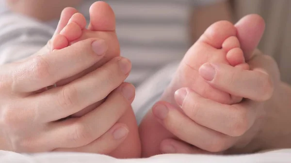 Baby feet in mother s hands. Feet of an infant, mom will embrace the baby with her arms. Happy Mother and her baby are playing together. Happy family concept. Childcare happy childhood. Family moments