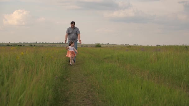 Happy family, dad and little daughter are playing, father catches up with child in park on green grass. Dad and baby are happy to run and walk outdoors. Dad walks with his beloved daughter at weekend. — Vídeo de Stock