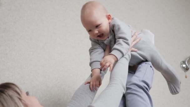 El niño y la madre juegan juntos, fantasean y sueñan con volar en avión. Mamá joven criando a un bebé lindo, hija jugando piloto en el sofá en casa. Divertido hijito volando en brazos de madres. Familia feliz — Vídeos de Stock