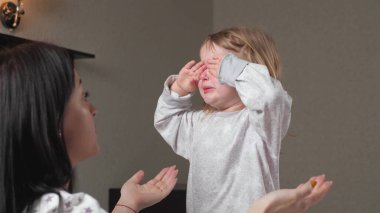 Çocuk, annesinin kollarında odada ağlıyor. Anne çocuğu sakinleştirir. Gözlerinde yaşlarla anneleri ve bebekleri annelerini duygusal olarak kucaklıyor. Sevgi dolu genç bir anne kucaklar ve onu rahatlatır.