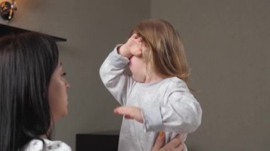 Çocuk, annesinin kollarında odada ağlıyor. Anne çocuğu sakinleştirir. Gözlerinde yaşlarla anneleri ve bebekleri annelerini duygusal olarak kucaklıyor. Sevgi dolu genç bir anne kucaklar ve onu rahatlatır.