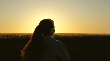 Sağlıklı güzel kız spor yapıyor, kırsalda koşuyor. Antrenman koşusu. Özgür genç bir kadın yazın şafak vakti parkta koşar kulaklıkla müzik dinler. Koşucu kız temiz hava soluyor.