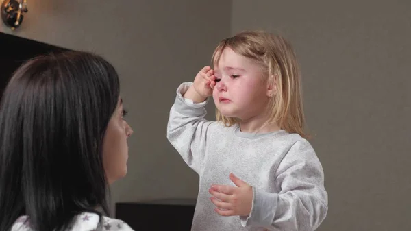 Çocuk, annesinin kollarında odada ağlıyor. Anne çocuğu sakinleştirir. Gözlerinde yaşlarla anneleri ve bebekleri annelerini duygusal olarak kucaklıyor. Sevgi dolu genç bir anne kucaklar ve onu rahatlatır.