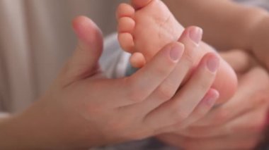 Bir bebeğin ayakları, anne bebeği kollarıyla kucaklayacak. Bebek ayaklar annenin ellerinde. Mutlu anne ve bebeği birlikte oynuyorlar. Mutlu aile kavramı. Çocuk bakımı mutlu bir çocukluk. Aile anları