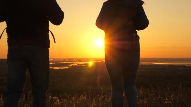 Ingyenes utazók, férfi és nő hátizsákkal, ereszkedjen le a hegyről a hajnal sugarai, élvezze a természetet, a gyönyörű nap és a táj. A gondtalan turisták naplementekor utaznak. Csapatmunka az üzleti életben. — Stock videók