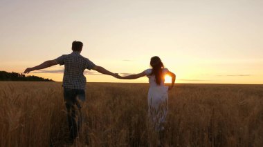 Mutlu evli çift buğday tarlasında el ele tutuşuyorlar. Takım konsepti iş dünyası özgürlük seyahat zafer mutluluk takım çalışması. Mutlu bir aile. Parkta gün batımında birbirini seven bir çift. Aile Takım Çalışması