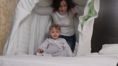 Mutlu aile çocuğu, kızı anne babası yatakta kürek çekiyor. Genç ebeveynler küçük bir çocukla oynarlar. Çocuk, anne örtünün altında saklanıyor, baba arıyor. Oyun oynarken aile gülüşü