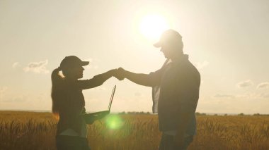 İş adamları birbirlerini selamlar, dışarıda çalışırlar. İki iş adamı, erkek ve kadın, sıkıca el sıkışıyorlar. Bir çiftçi ve işadamı buğday tarlasında konuşur, anlaşma yapar, tablet kullanır. Anlaştık..