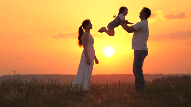 Papà vomita la sua amata figlia, il bambino felice ride e gioisce, abbraccia papà. Bambino, padre, mamma. La famiglia felice sta giocando nel parco al tramonto. Padre e figlia giocano, sognano di volare — Video Stock