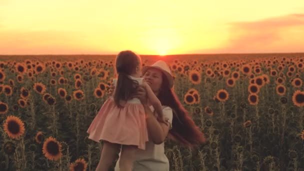 Szczęśliwa rodzina, matka krążąca wokół swojej szczęśliwej córki w ramionach na polu słoneczników. Rolnicy matka bawi się z dzieckiem w słońcu na polu słonecznym. Zdrowa rodzina podróżuje latem na świeżym powietrzu. — Wideo stockowe