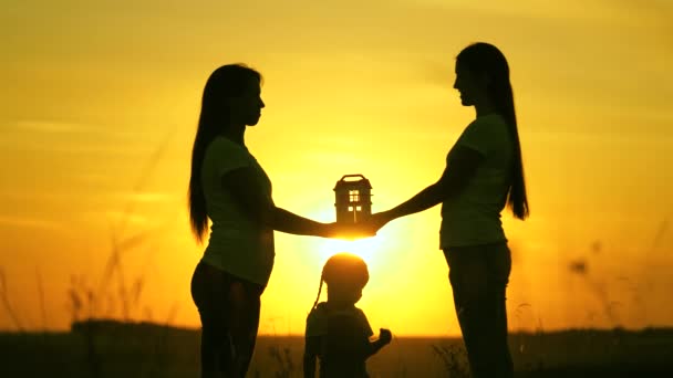 Mãe de família feliz e crianças segurar uma casa de sela com suas próprias mãos. Jogos de família e sonhos de casa e saúde e amor ao pôr do sol. Conceito de empréstimos e seguro imobiliário para famílias jovens. — Vídeo de Stock