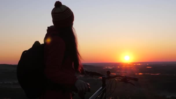 Спортивні розваги Велосипедні велосипеди на заході сонця. Жінка з велосипедом, мандрівник, спортсмен відпочиває на вершині гори, милуючись схід сонця. Безкоштовна дівчина-велосипедистка розслабляється і насолоджується пейзажами вершини — стокове відео