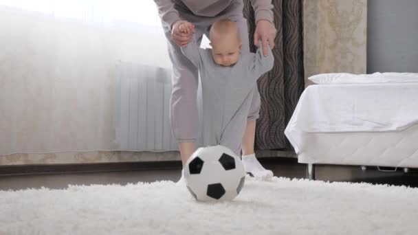 Mutter und kleines Kind, Sohn spielen Fußball im Zimmer, kicken Fußball. Kind, Säugling, spielt gerne mit seiner Mutter zu Hause. Glückliche, gesunde, sportliche Familie. Entwickeln Sie Ihr Kind durch aktive Sportspiele — Stockvideo