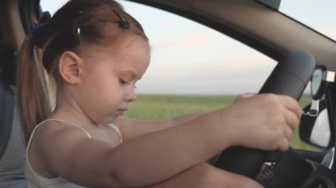 Babası küçük kızına direksiyon simidini çevirmeyi öğretiyor hem de sürücü koltuğunda otururken. Babam çocuklarla arabayla seyahat eder. Şoförle çocuk sürüyor. Mutlu aile ve çocukluk kavramı