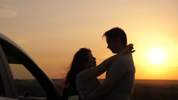 Heureux voyageurs amoureux homme et femme se tiennent à côté de la voiture et admirer le beau coucher de soleil au camping. Les touristes voyagent en voiture, s'embrassent, admirent le lever du soleil, la nature. Voyageurs gratuits, touristes. Voyage en famille en voiture. — Video
