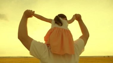 Baba gün batımında kızıyla birlikte omuzlarında yürüyor. Mutlu aile parkta dinleniyor. Babam sevgili çocuğunu güneşte boynuna takıyor. Ailesi olan bir çocuk hafta sonları yürür.