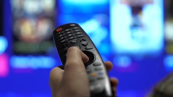 Man Watching Smart TV And Using Modern Black Remote Controller, Blurred TV In The Background. Close Up View - DCi 4K Video — Stock Video