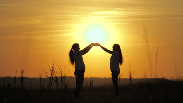 As raparigas têm um lindo sol nas palmas das mãos. Conceito de família, vida, calor, esperança. A mãe e a filha tocaram as palmas das mãos umas das outras, entregaram um lindo pôr-do-sol. Família feliz mãe e filha — Vídeo de Stock