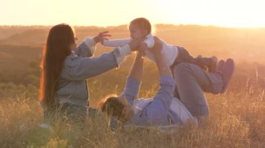 Anne ve baba dışarıda oynuyorlar. Mutlu aile gün batımında çimlerin üzerinde küçük kızlarıyla oynuyorlar. Çocuk babaya tırmanıyor. Kız, anne ve babasına sarılıp onu seviyor..