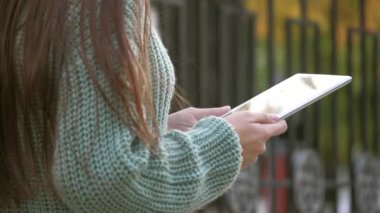 Şehir caddesinde dijital tablet baskı mesajları kullanan bir iş kadını. Öğrencilerin elleri tabletin ekranına dokunuyor. Tabletle çalışan serbest çalışan kadın kaldırımda yürüyor..