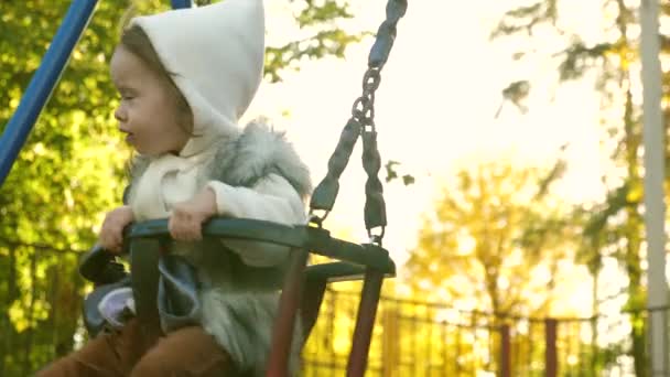 Bonne famille maman roule le petit enfant en vol sur balançoire dans le parc. Le week-end, mère et fille marchent. Promenades en famille dans le parc. Enfant et jeune parent. concept d'enfants et de famille. Travail d'équipe — Video