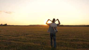 Baba kızıyla oynar, tarlada koşar ve sevgili kızını sırtüstü çevirir, çocuk sevinir ve güler. Mutlu çocuk baharda gün batımında babasıyla birlikte tarlada oynuyor. Mutlu aile