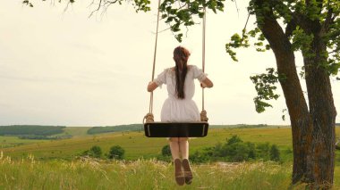 Akşam parkında salıncakta sallanan genç bir kız. Tahta salıncakta sallanan özgür, mutlu bir kadın. Salıncakta sallanmak, uçma hayalleri. İlkbaharda doğada seyahat etmek. Sağlıklı yaşam tarzı