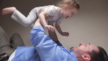 Kaygısız, sevgi dolu bir aile babası. Küçük, tatlı bir çocuk babası. Süper kahraman bir uçak gibi yere yatıp eğleniyor.