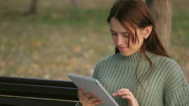 Öğrencinin elleri parktaki bankta bulunan tabletin dokunmatik ekranına dokunur. Dijital tablet kullanan bir kız şehir caddesinde mesaj basıyor. Dışarıda tablet bilgisayarla çalışan bir kadın.