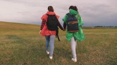Özgür kadınlar doğada seyahat eder, yaz aylarında tarlada yürürler. Gezginlerin takım çalışması. Macera ve seyahat konsepti. Kaygısız turistler tatilde sırt çantalarıyla seyahat eder, hafta sonu parkta..