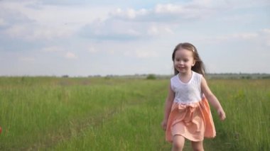 Çocuk kız yazın çayırda yeşil çimlerde koşar. Mutlu bir aile ve çocukluk. Mutlu küçük kız sahada oynuyor. Çocukluk hayalleri. Sağlıklı bir çocuk dışarıda oynar. Kızım parkta oynuyor.