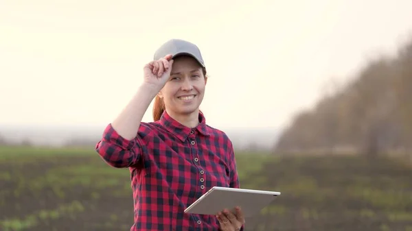 Farmer nő dolgozik egy számítógépes táblagép, mosolyog a kamera. Egy okos agronómus táblagéppel a kezében ellenőrzi a terepet. Környezetbarát mezőgazdaság. Modern digitális technológiák a mezőgazdaságban — Stock Fotó