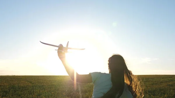Glückliches Mädchen rennt mit Spielzeugflugzeug über Feld im Sonnenuntergang. Kinder spielen in Spielzeugflugzeugen. Teenager träumt davon zu fliegen und Pilot zu werden. Mädchen will Pilotin und Astronautin werden. Zeitlupe — Stockfoto