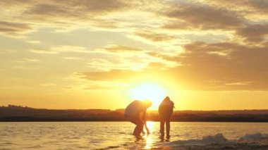 Girls play with paper boats. Children put a paper boat into water. Childs hands launches a boat in park into river. Paper fleet. Happy family fantasy, childhood dream, adventure and travel concept.
