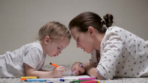 Bambino e mamma, tata, insegnano alle ragazze a disegnare. Famiglia felice che gioca insieme a casa sul pavimento. Una madre aiuta sua figlia a imparare a disegnare sulla carta, colorando con matite multicolori e pennarelli.. — Video Stock
