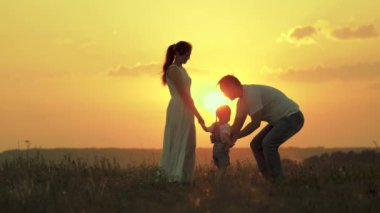 Parkta çocuklu mutlu bir aile. Baba ve anne küçük kızlarıyla oynuyorlar, baba bebeğe sarılıyor. Mutlu anne ailesini seviyor. Anne, baba ve çocuk hafta sonu, aile dışarıda dinleniyor.