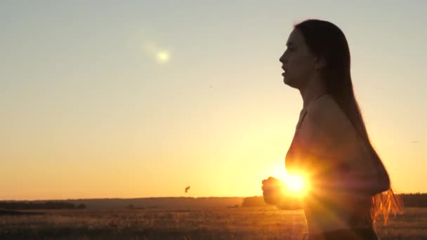 Running after sun. Training jogging. Free young woman runs in summer park at sunset. A healthy beautiful girl is engaged in fitness, jogging in country in sun. Jogger girl breathes fresh air on field. — Stock Video