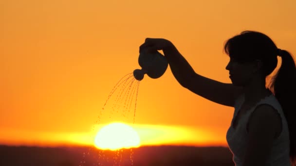 Una mujer vierte agua en el sol de una regadera. La chica juega vierte agua en el sol. El hombre crece el sol. Jardinero, granjero. Amanecer. El concepto de vida, paz, bondad. Hermoso atardecer. — Vídeo de stock