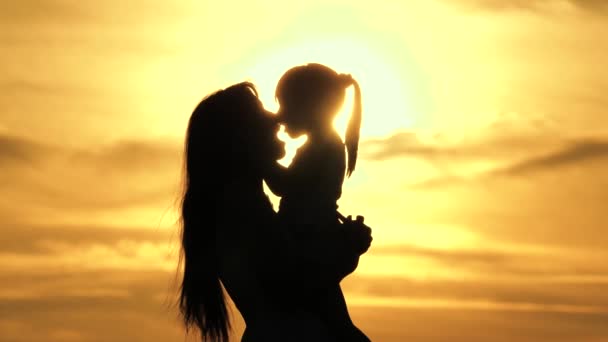 Щаслива мати й маленька дитина бавляться, обіймаючи природу в променях сонця. Щаслива родина. Мама кружляє навколо своєї улюбленої дочки на руках. Мама з дитиною силует, дитинство, материнство. — стокове відео