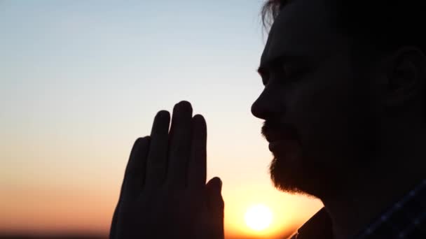 Homme chrétien priant au coucher du soleil close-up. Des hommes devant le ciel dans les rayons du soleil prient pour leur famille et leurs enfants. Détente et méditation dans la nature, mode de vie sain — Video