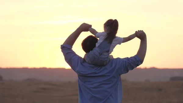 Dziecko i tata bawią się razem w parku na świecie, szczęśliwa rodzina. Dziecko, córka, siedzi na szyi ojca, macha rękami, lata jak samolot. Beztroski ojciec i Kid Walking w lecie — Zdjęcie stockowe