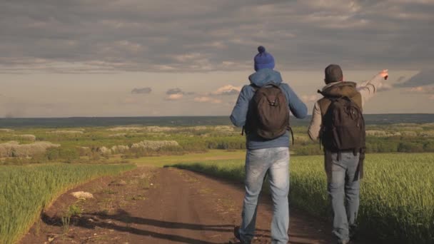 Travelers with backpacks are walking along road. Teamwork. Hikers travel along a country road and admire beautiful landscape. Adventure and travel concept. Tourists enjoy relaxation and nature — Stock Video